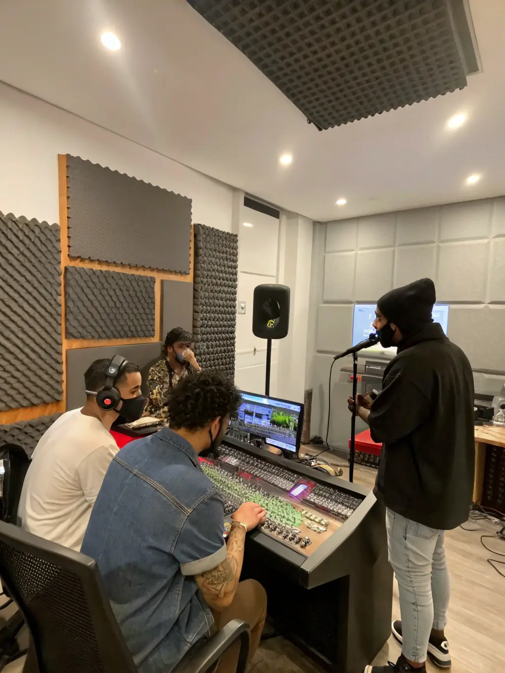 A recording session in a professional studio, featuring young musicians working on their original compositions with guidance from experienced producers.